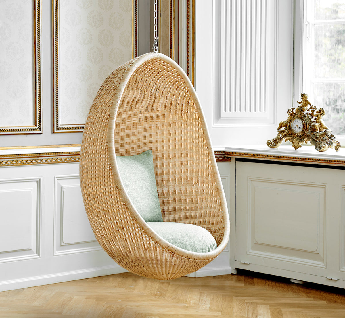 Dette er et livsstilsbillede af Hanging Hængeæg-stol i natural core weave Rattan frame, i et elegant klassisk interiør med forseggjorte forgyldte.