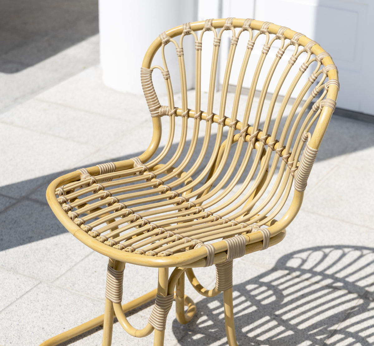 Dette er et livsstilsbillede af Rita Udendørs spisebordsstol i natural aluminium artfibre. Kombineret med et bistrobord på en hvid kolonneterrasse.