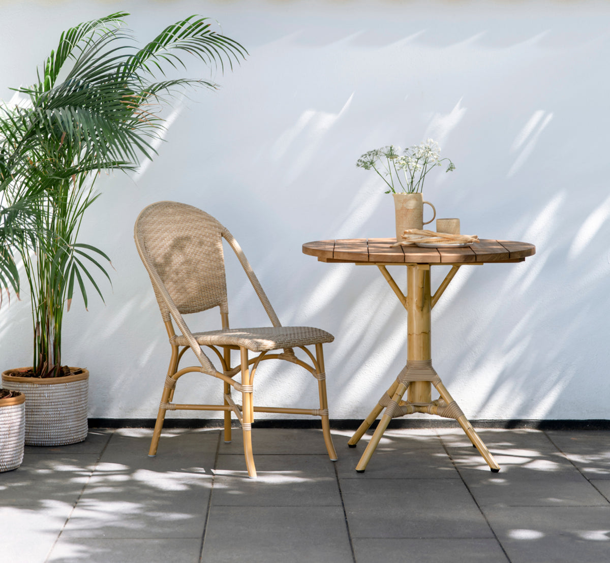 Dette er et livsstilsbillede af Nicole Cáfe Table | Teak Ø80 cm i natural aluminium artfibre. Stylet i et lyst interiør.