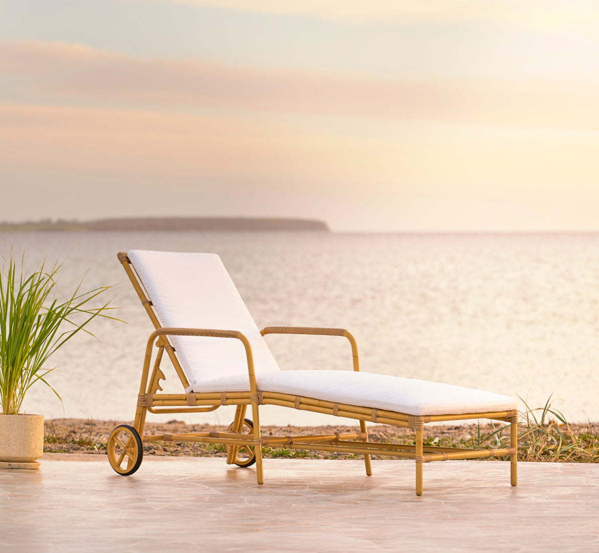 Dette er et livsstilsbillede af Josephine Solseng i natural aluminium artfibre, på en kystterrasse af natursten ved solnedgang med havudsigt og.
