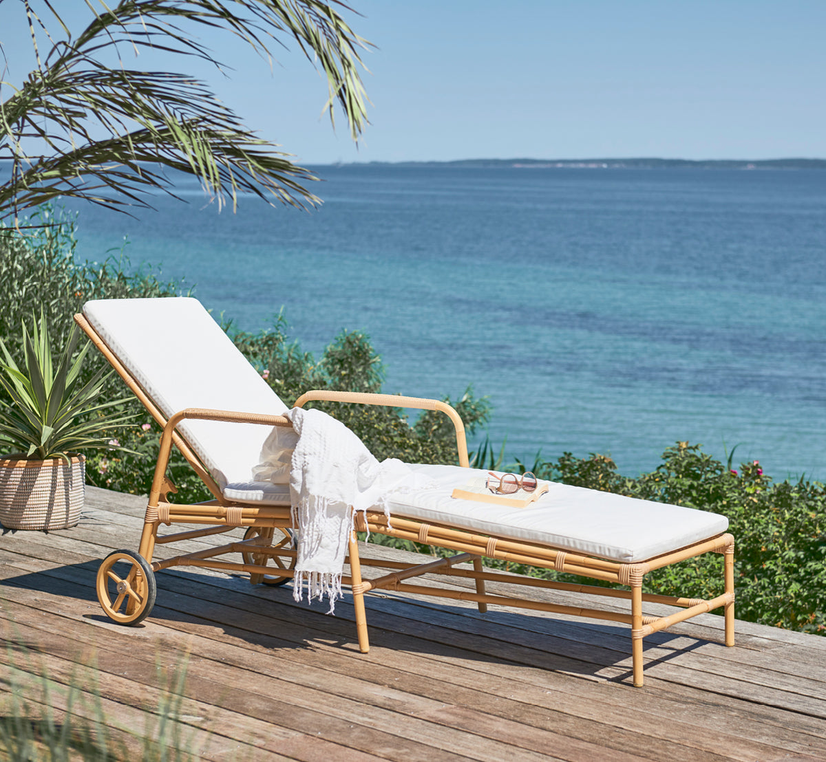 Dette er et livsstilsbillede af Josephine Solseng i natural aluminium artfibre, på en kystterrasse af natursten ved solnedgang med havudsigt og.