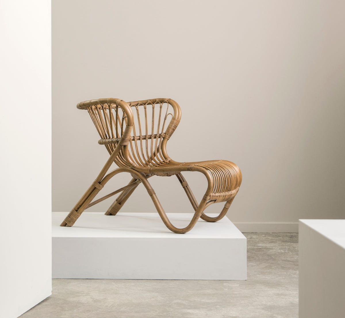 Dette er et livsstilsbillede af Fox Lænestol i polished Antique Rattan, i et varmt interiør med okkerfarvet lambrisering og mørkt sildebensgulv.