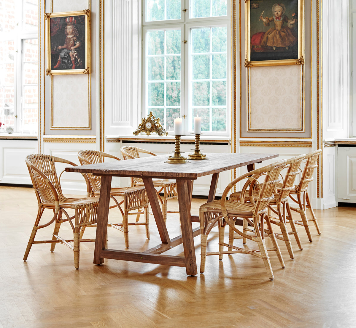 Dette er et livsstilsbillede af Robert Spisebordsstol i polished antique rattan. Placeret ved siden af en høj terrakotta-urne på et sildebensparketgulv.