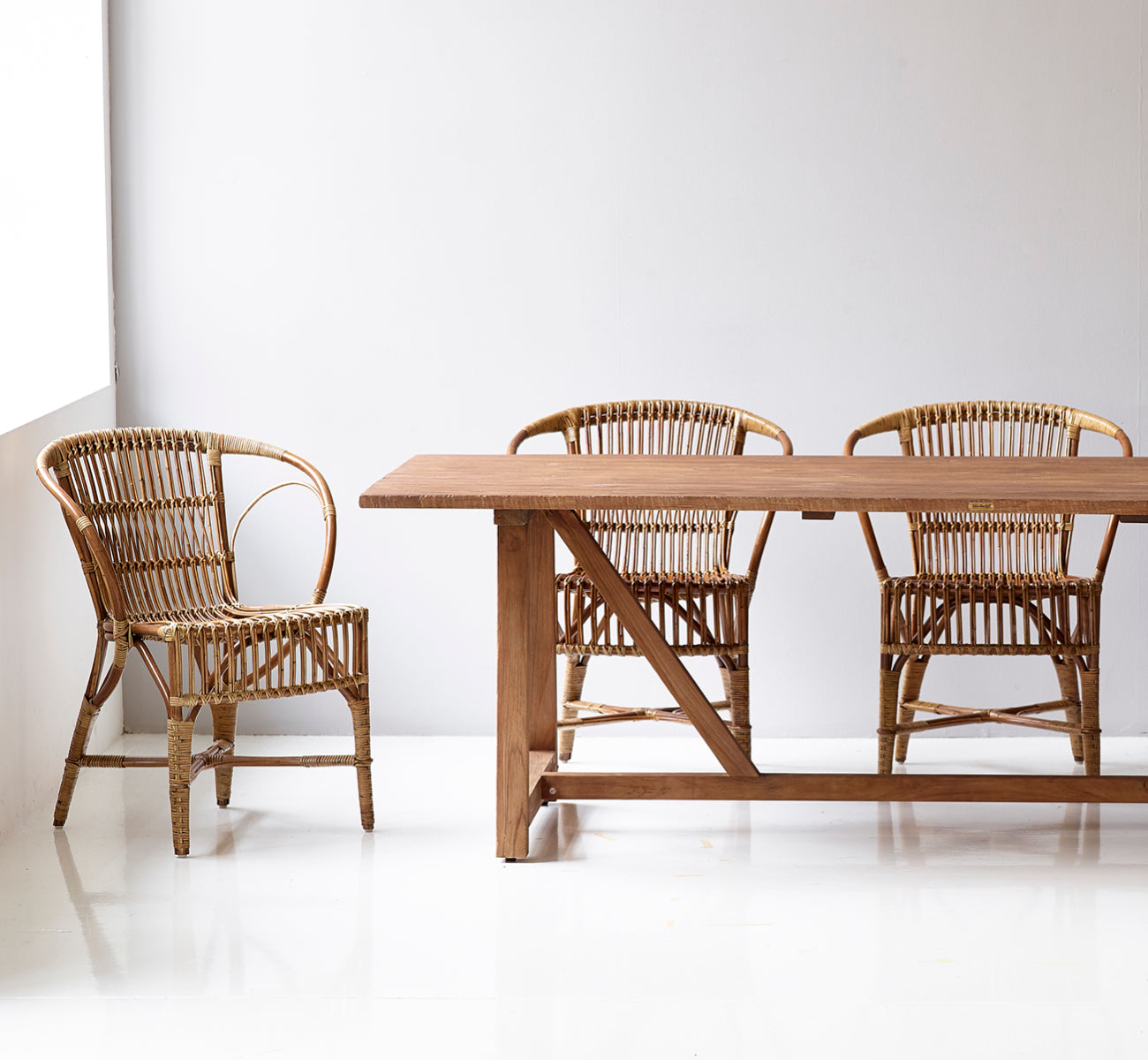 Dette er et livsstilsbillede af Robert Spisebordsstol i polished antique rattan. Placeret ved siden af en høj terrakotta-urne på et sildebensparketgulv.